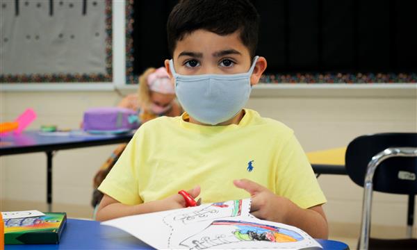boy smiles while wearing mask